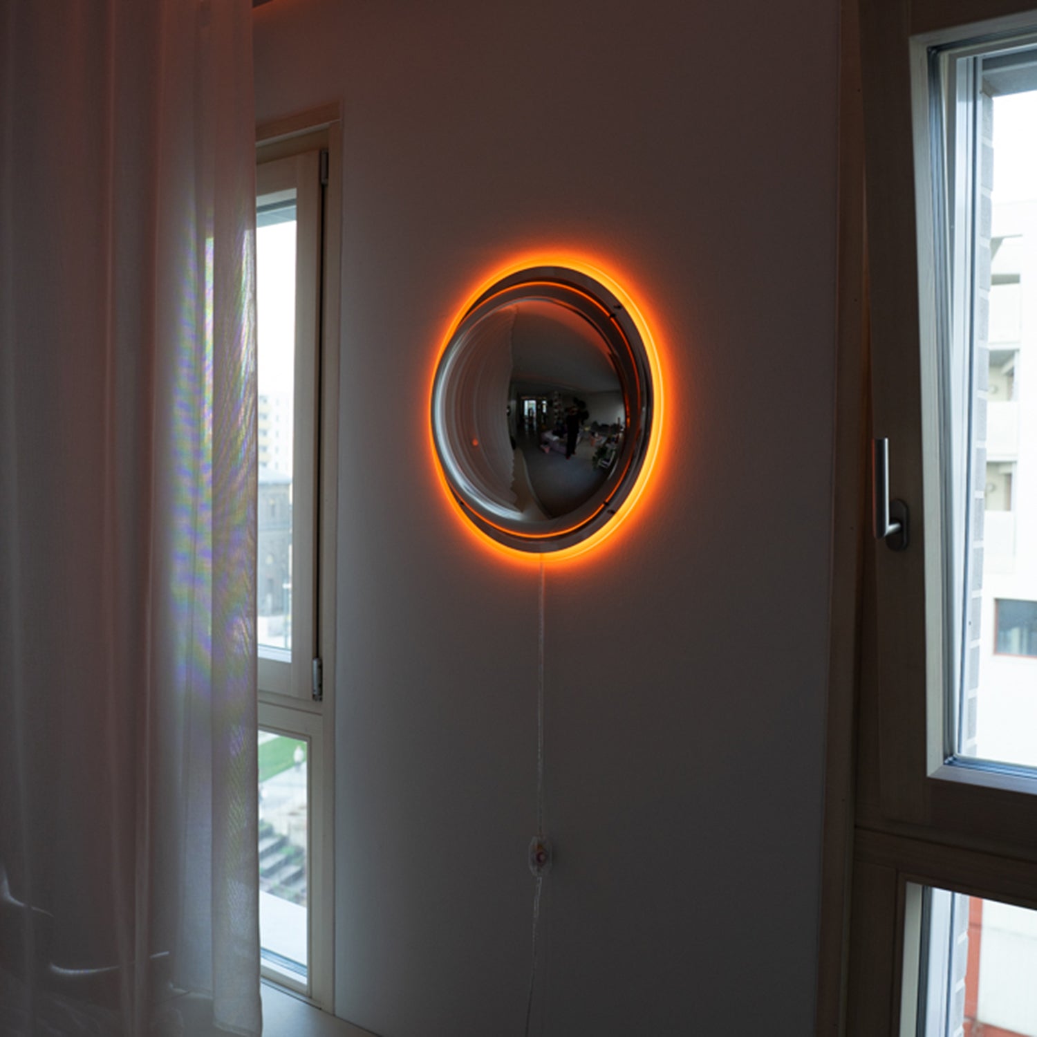 BUBBLE Wandlampe zwischen zwei Fenstern – orangener Halo, modernes Apartment bei Tageslicht