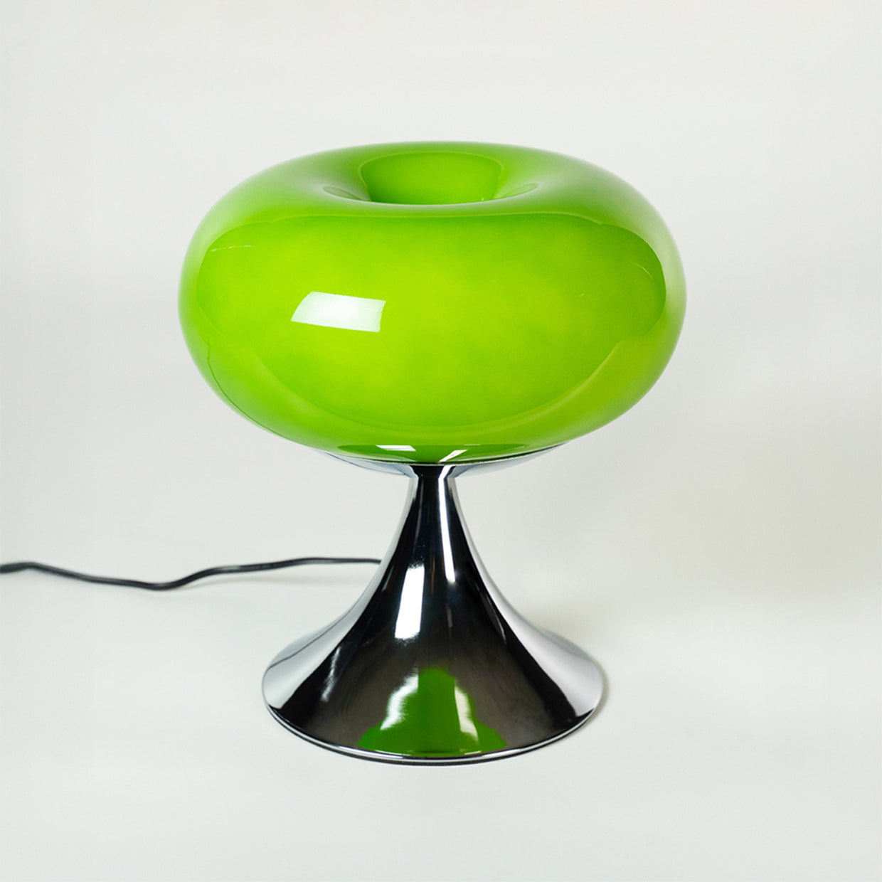 Runde, glänzend grüne Glasleuchte mit trompetenförmigem Chromfuß im Mid-Century-Stil. Retro-Design inspiriert von den 70er Jahren, perfekt als dekorative Nachttischlampe oder Wohnzimmerleuchte.