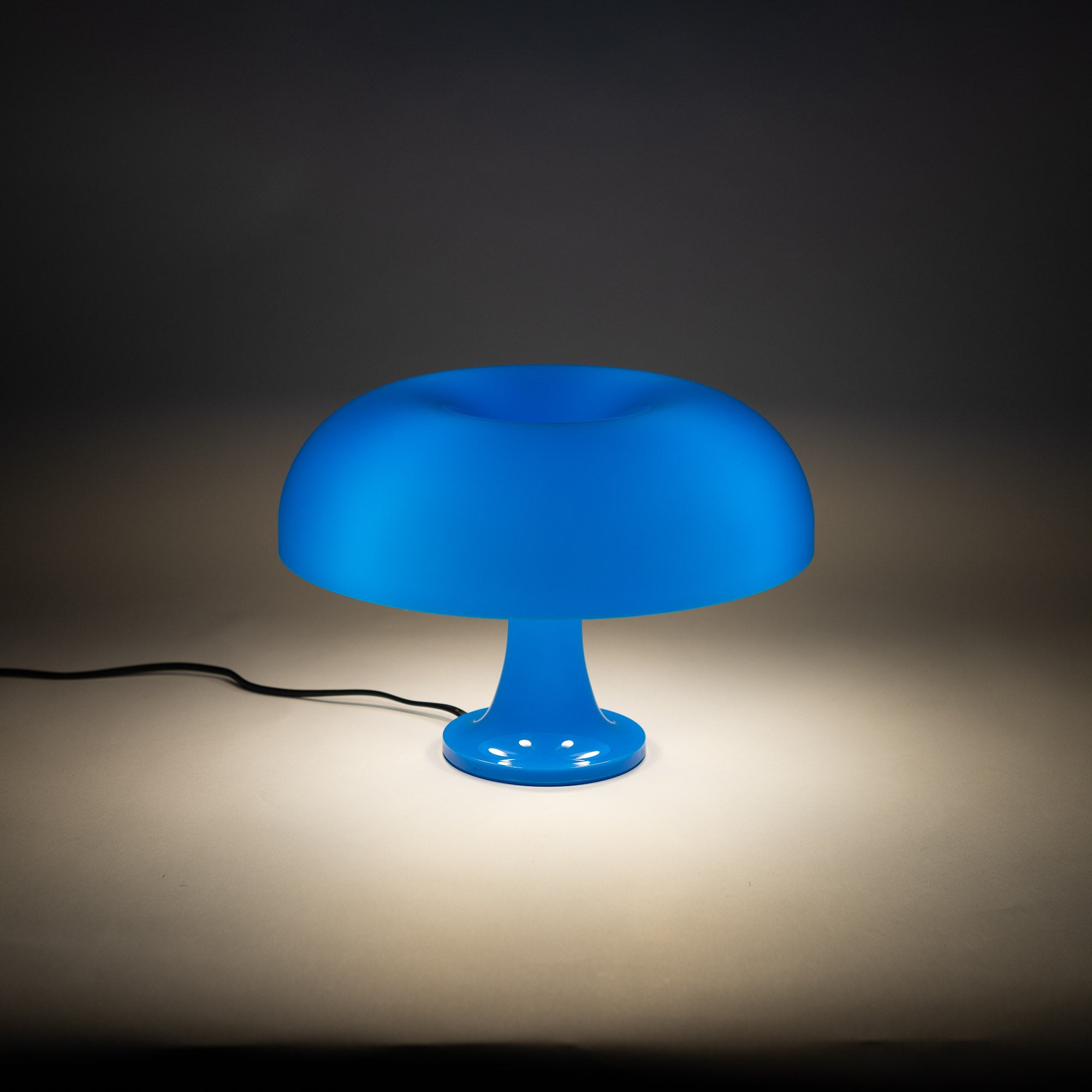 Die blaue Pilzlampe strahlt weiches Licht aus und schafft eine beruhigende Atmosphäre. Perfekt für ein stilvolles Wohn- oder Schlafzimmer. Minimalistisches Ambiente mit warmem Kontrast.