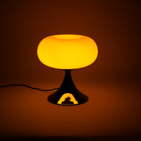 Die Lampe strahlt warmes Licht aus und erzeugt eine sanfte, gemütliche Atmosphäre. Ihr glänzender Chromfuß reflektiert das Licht, das in den Raum abstrahlt.