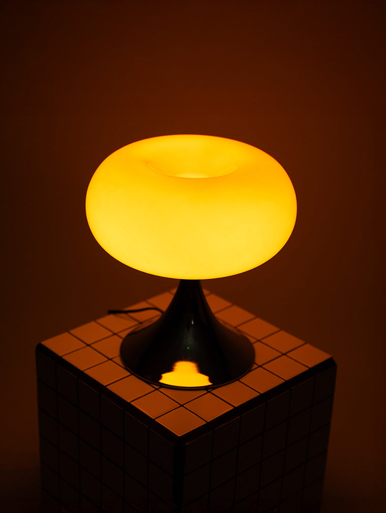 Die eingeschaltete orange Donut Lampe verbreitet weiches Licht auf einer neutralen Fläche. Ihr sanftes Leuchten sorgt für eine gemütliche Atmosphäre, ideal als stilvolles Nachtlicht oder dekorative Akzentbeleuchtung.