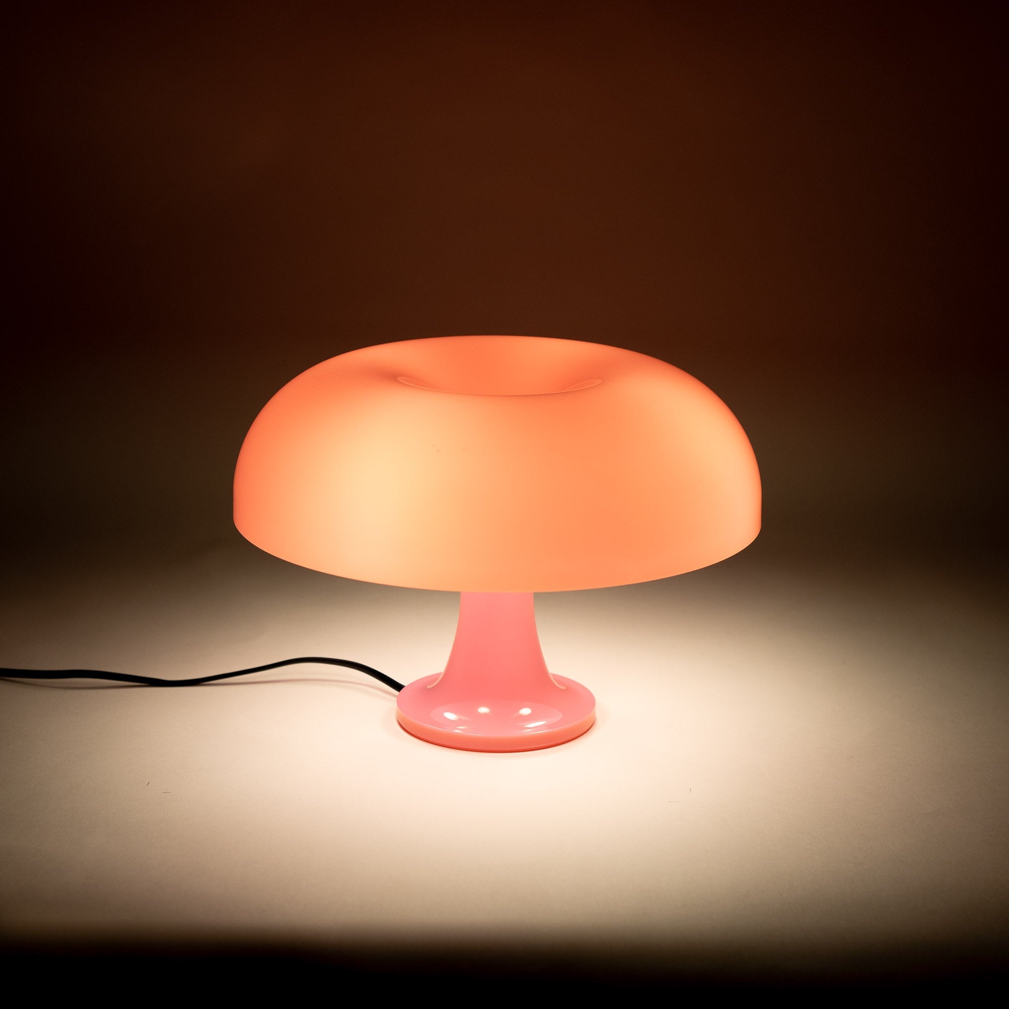 Die eingeschaltete Pilzlampe verbreitet weiches Licht auf einer neutralen Fläche. Ihr sanftes Leuchten sorgt für eine gemütliche Atmosphäre, ideal als stilvolles Nachtlicht oder dekorative Akzentbeleuchtung.