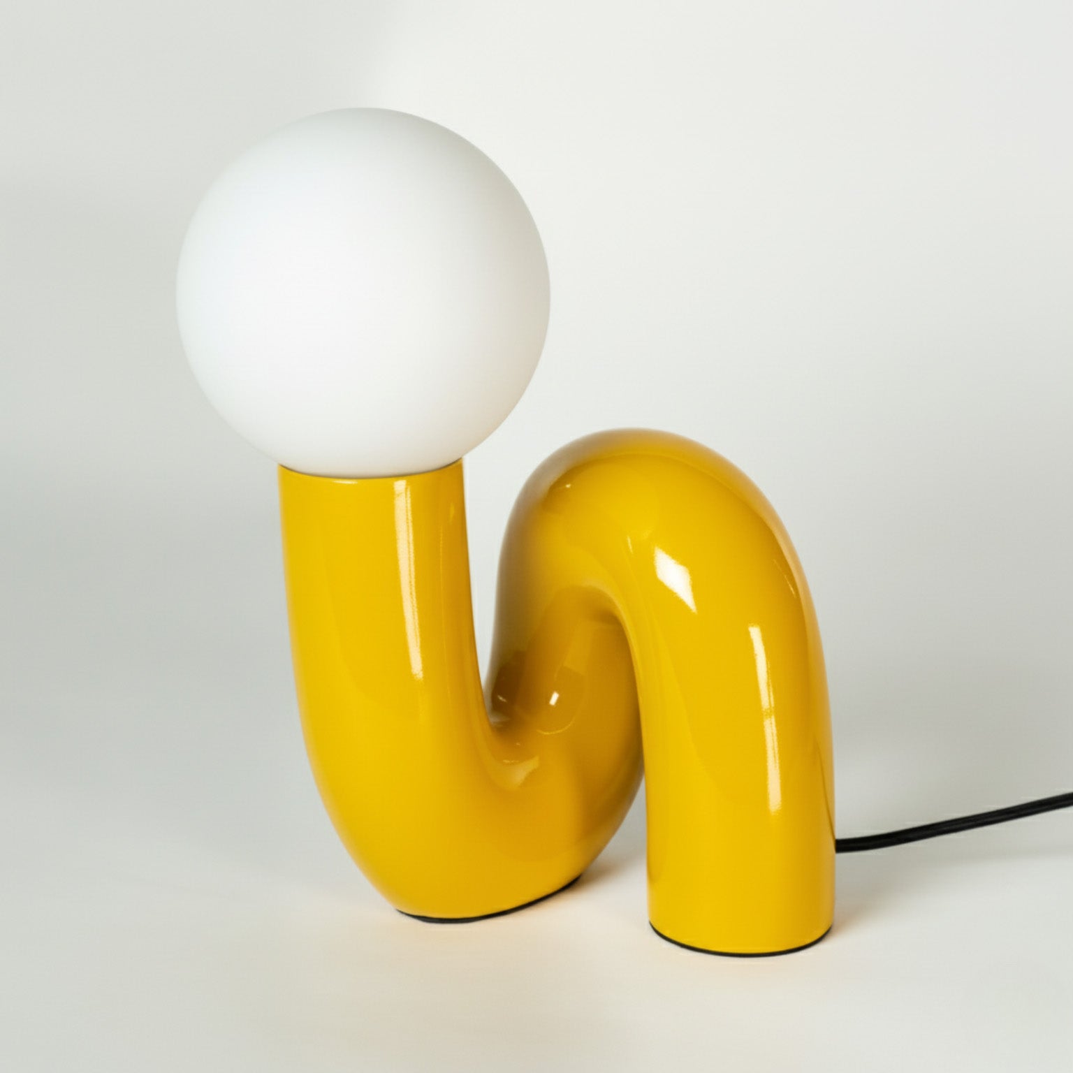 Retro Tischlampe Snake in Gelb von GLOW UP STUDIO – organische Lampe mit weißem Kugel-Leuchtkopf im Space Age Design, freigestellt vor weißem Hintergrund.