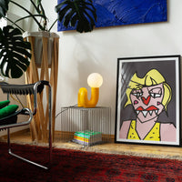 Retro Tischlampe Snake in Gelb von GLOW UP STUDIO – organische Designlampe mit Kugel-Leuchtkopf auf modernem Metalltisch, Wohnzimmer mit Kunst, Pflanzen und Teppich.