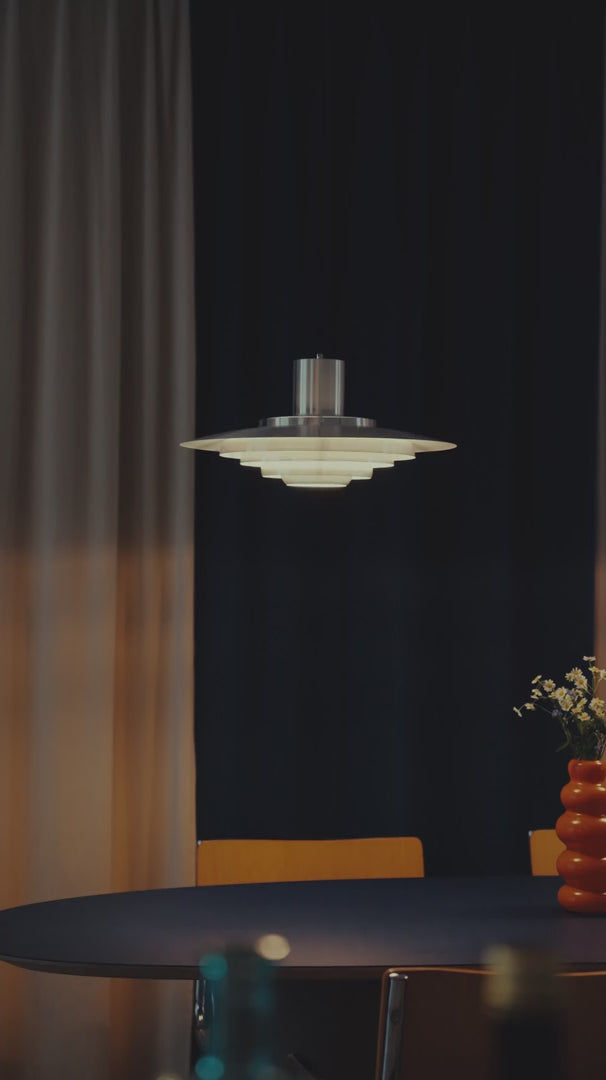 Hängelampe im Space Age Design aus gebürstetem Metall mit gestuften, runden Schirmen. Die Lampe erzeugt warmes, indirektes Licht und kombiniert skandinavischen Stil mit Mid-Century-Ästhetik. Perfekt über dem Esstisch platziert in einer Altbau Wohnung.
