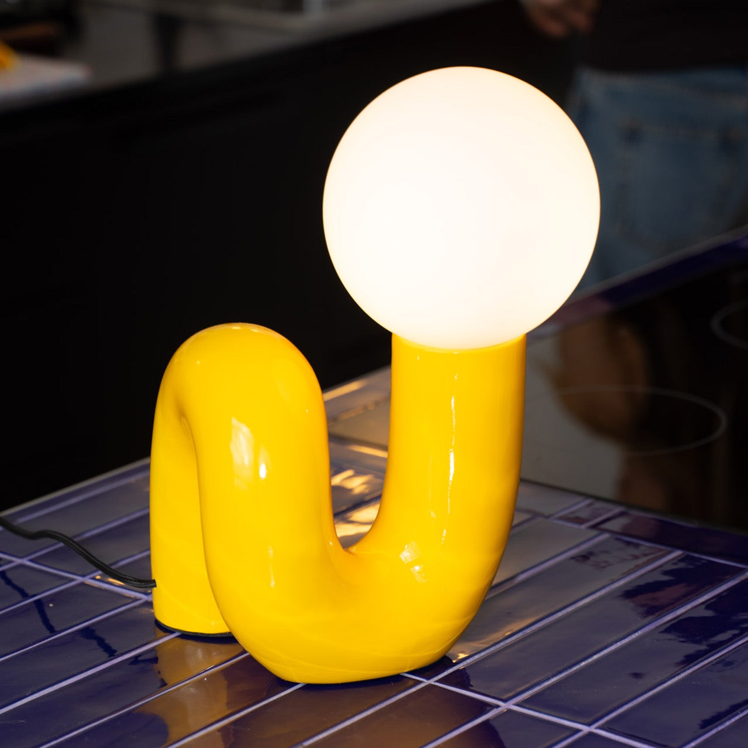 Detailaufnahme der Snake Lampe Gelb mit leuchtender Glaskugel im Space-Age Design.