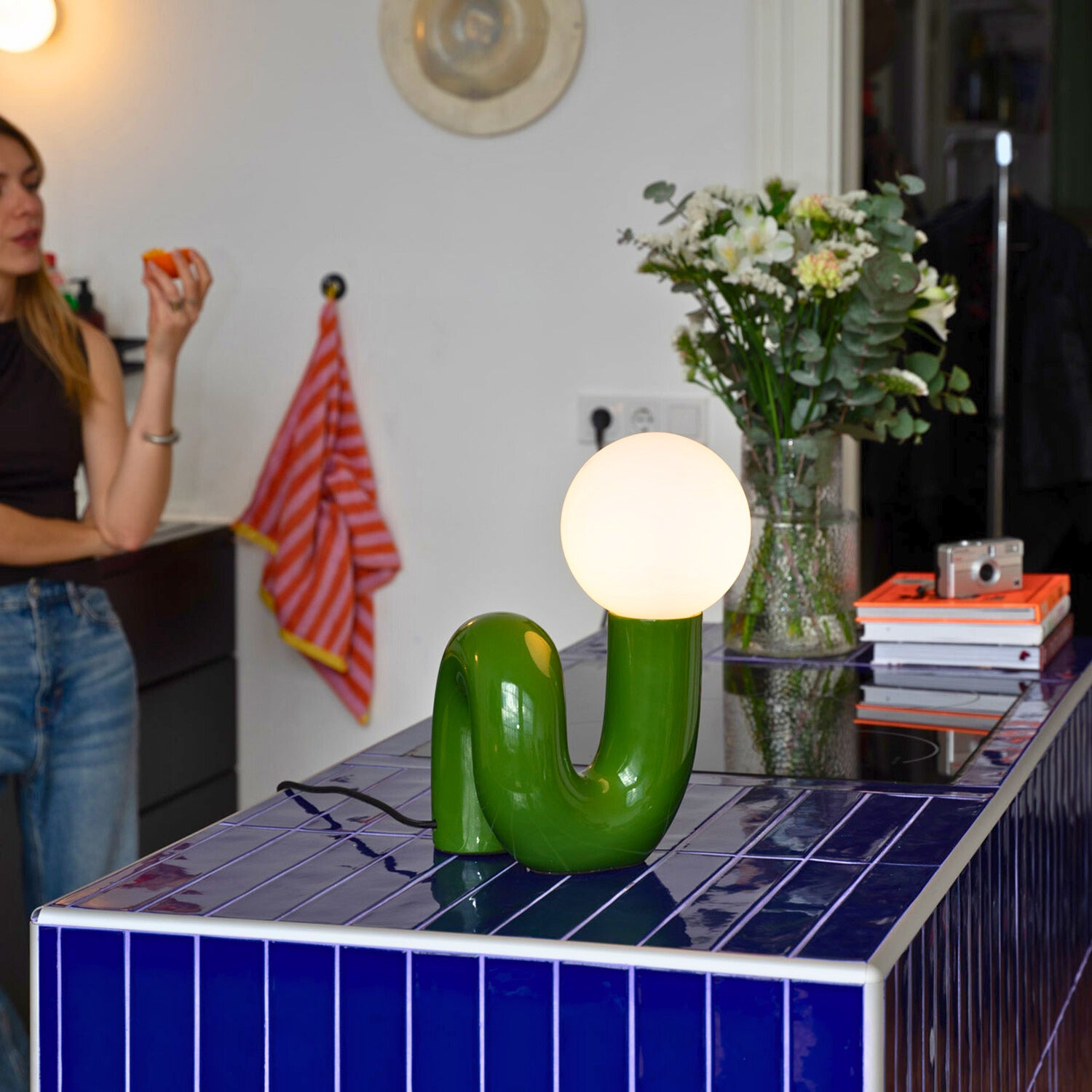 Snake Lampe Grün mit warmem Licht auf blauem Fliesentisch in moderner Küche im 60s Stil.