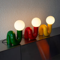 Snake Lampen in Gelb, Grün und Rot im 60s Retro Design auf grüner Kommode arrangiert.